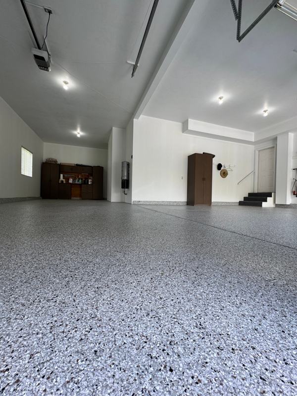 Gray flake garage floor with brown cabinets and a step to the house