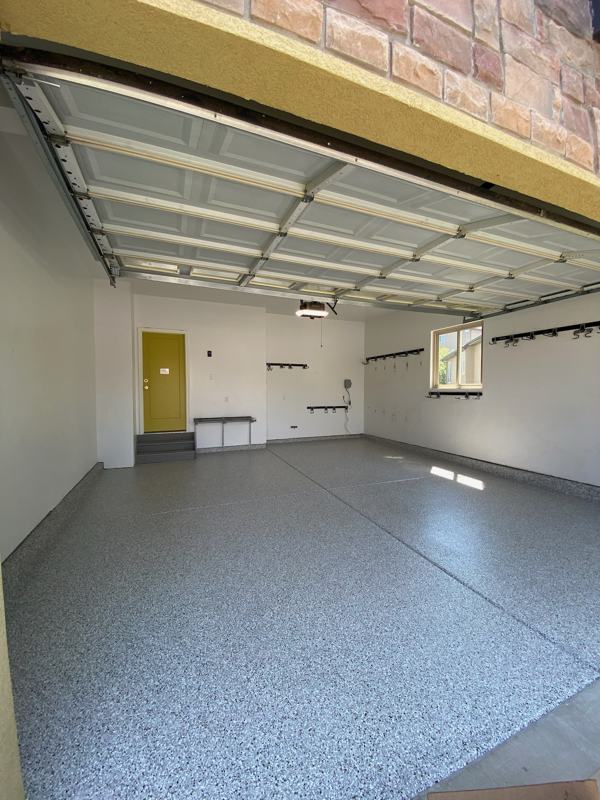 Wide view of a gray flake garage floor and a yellow entry door